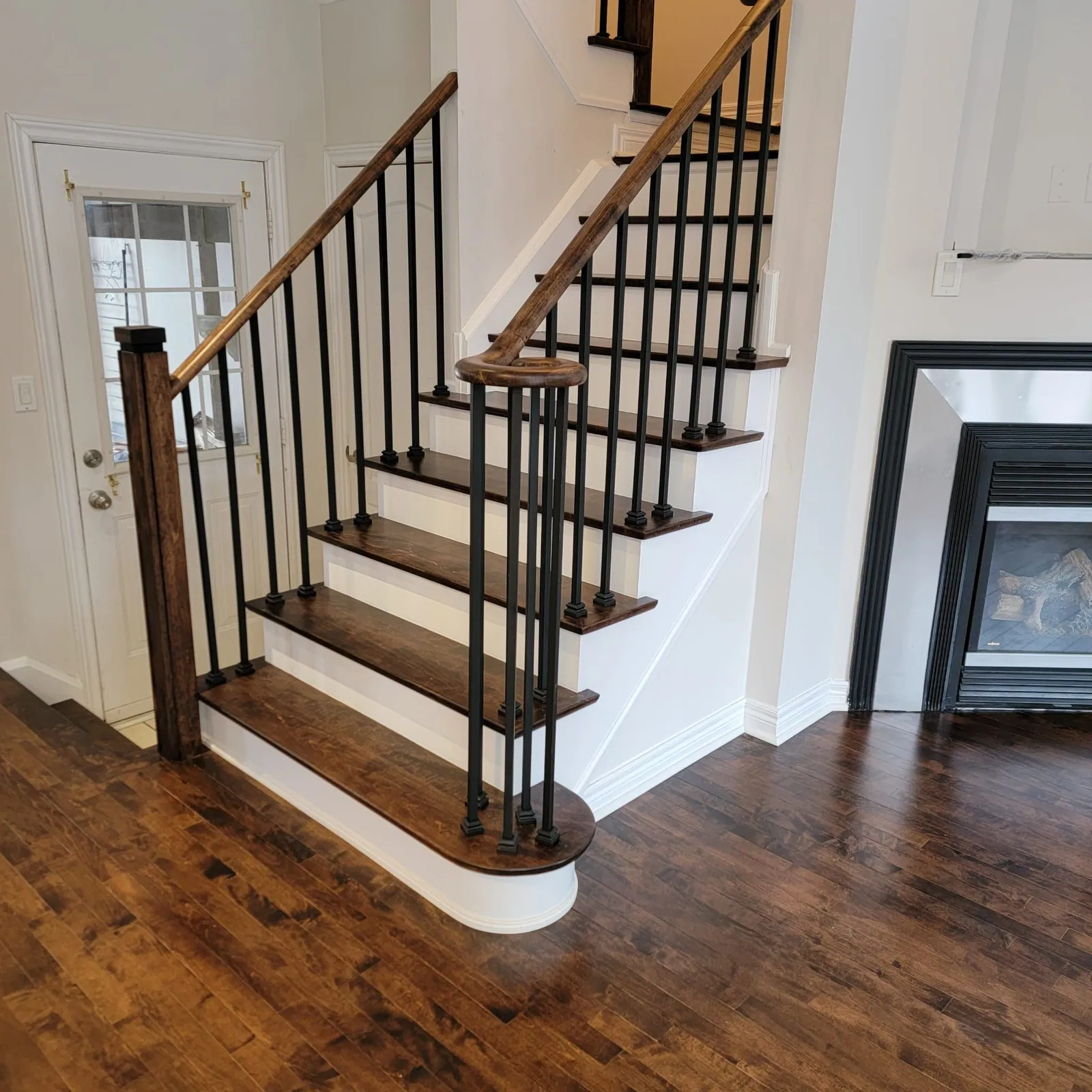 Dark treads with a bullnose first step and iron balusters.
