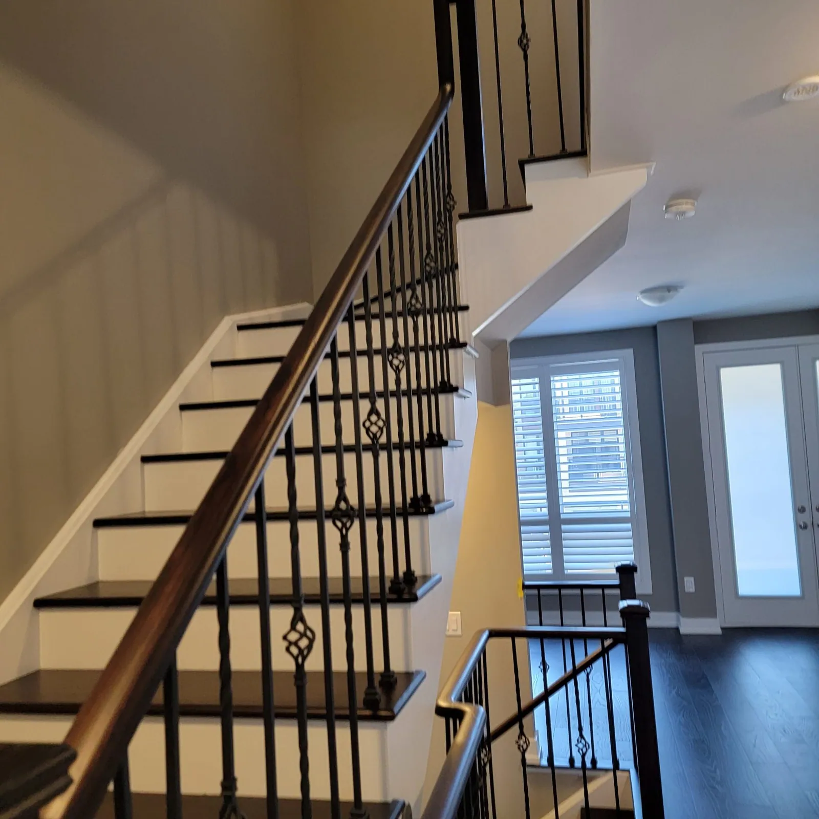 Dark treads with iron balusters up to a landing.