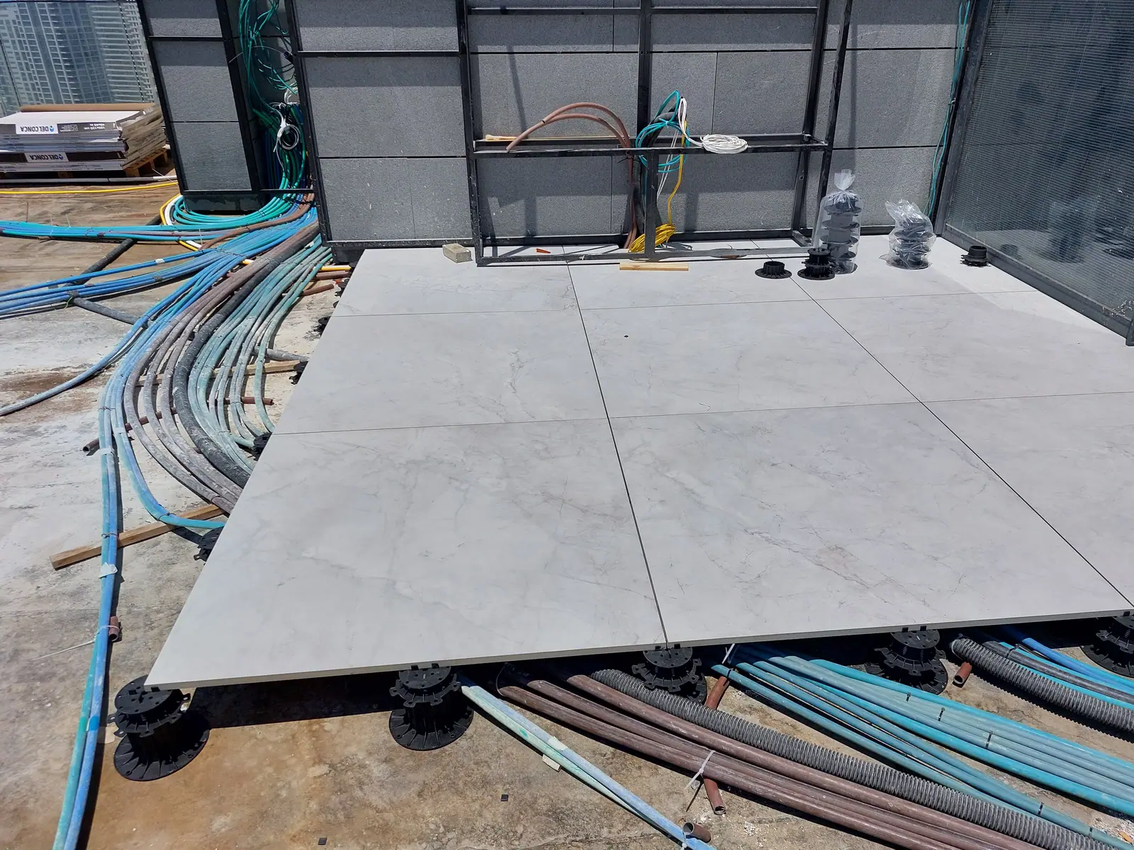Pavers on pedestals with pipes and conduit running underneath.