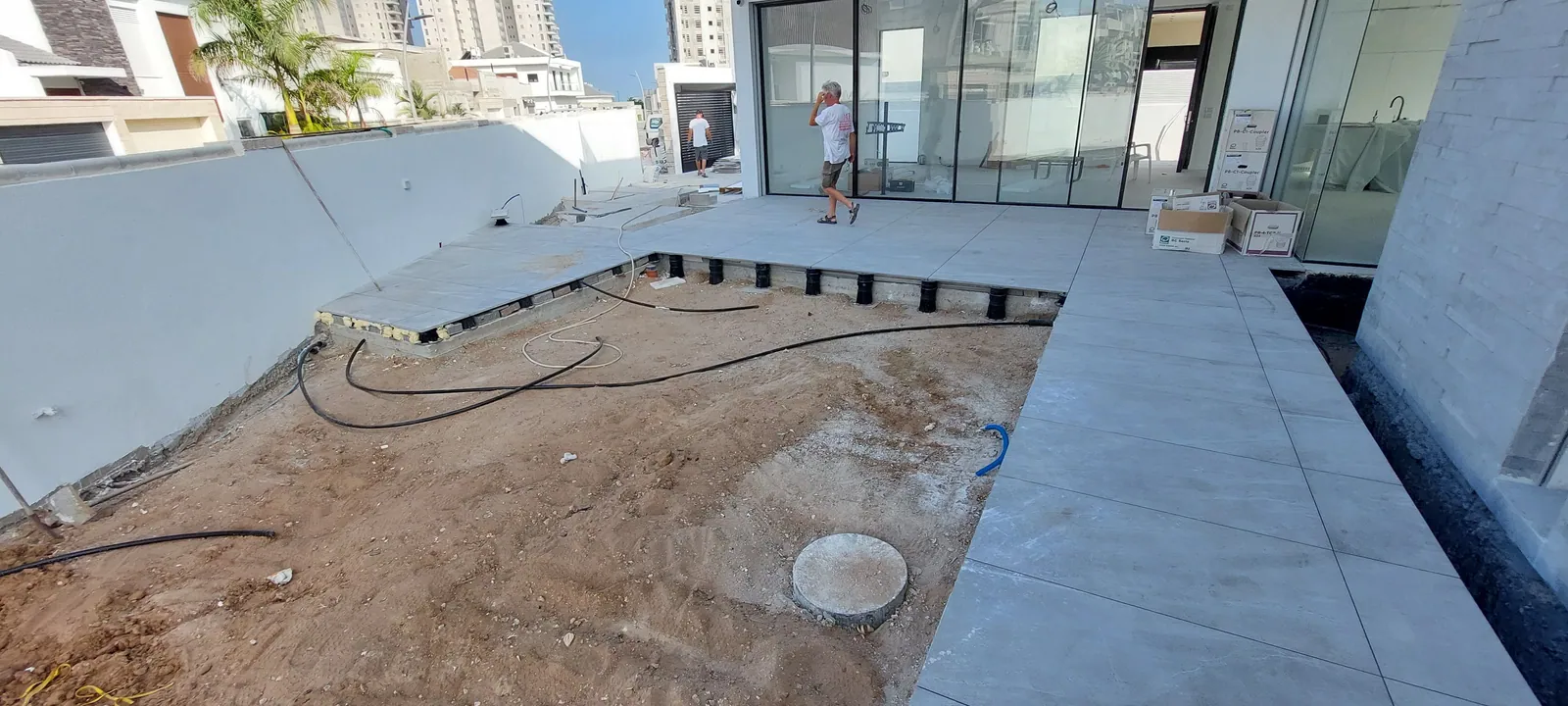 Pool deck pavers set on pedestals over a dirt base.