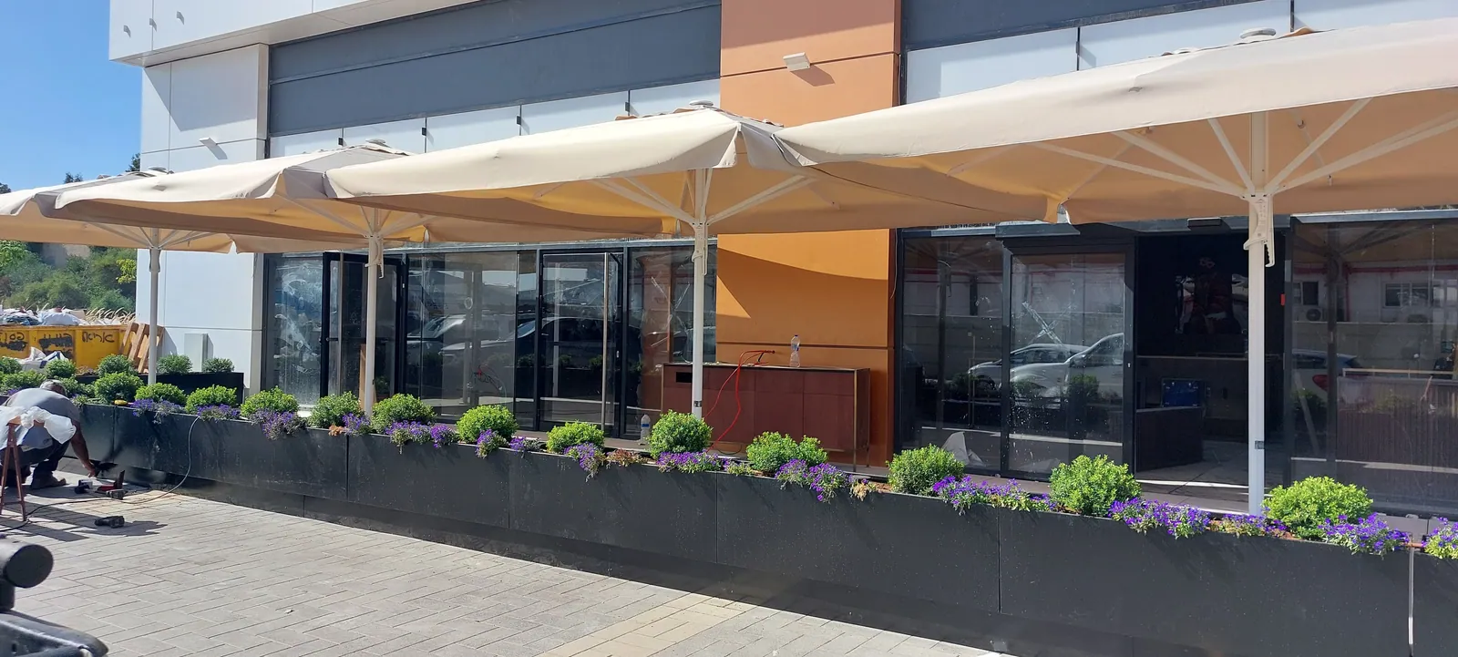 Restaurant patio with planters and umbrellas on a raised floor.