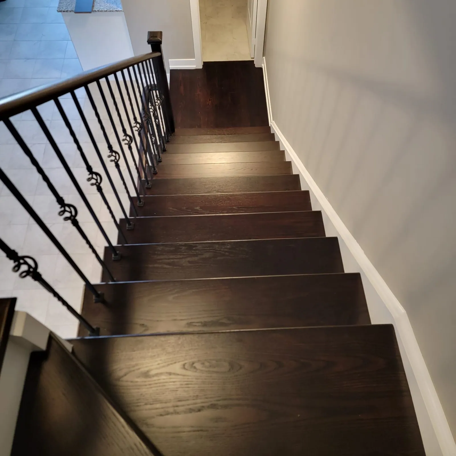 Straight stair with dark treads and an iron railing.